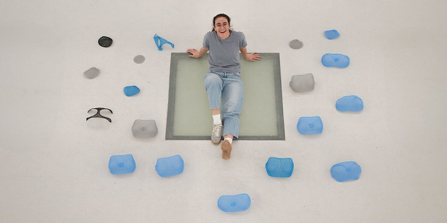 Beatriz Jerez Arnau liegt auf dem Boden um sie herum verschiedene Brustschutzschalen in blau und grau. 